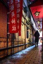A woman walks away from a Shinto shrine in a Tokyo alleyway